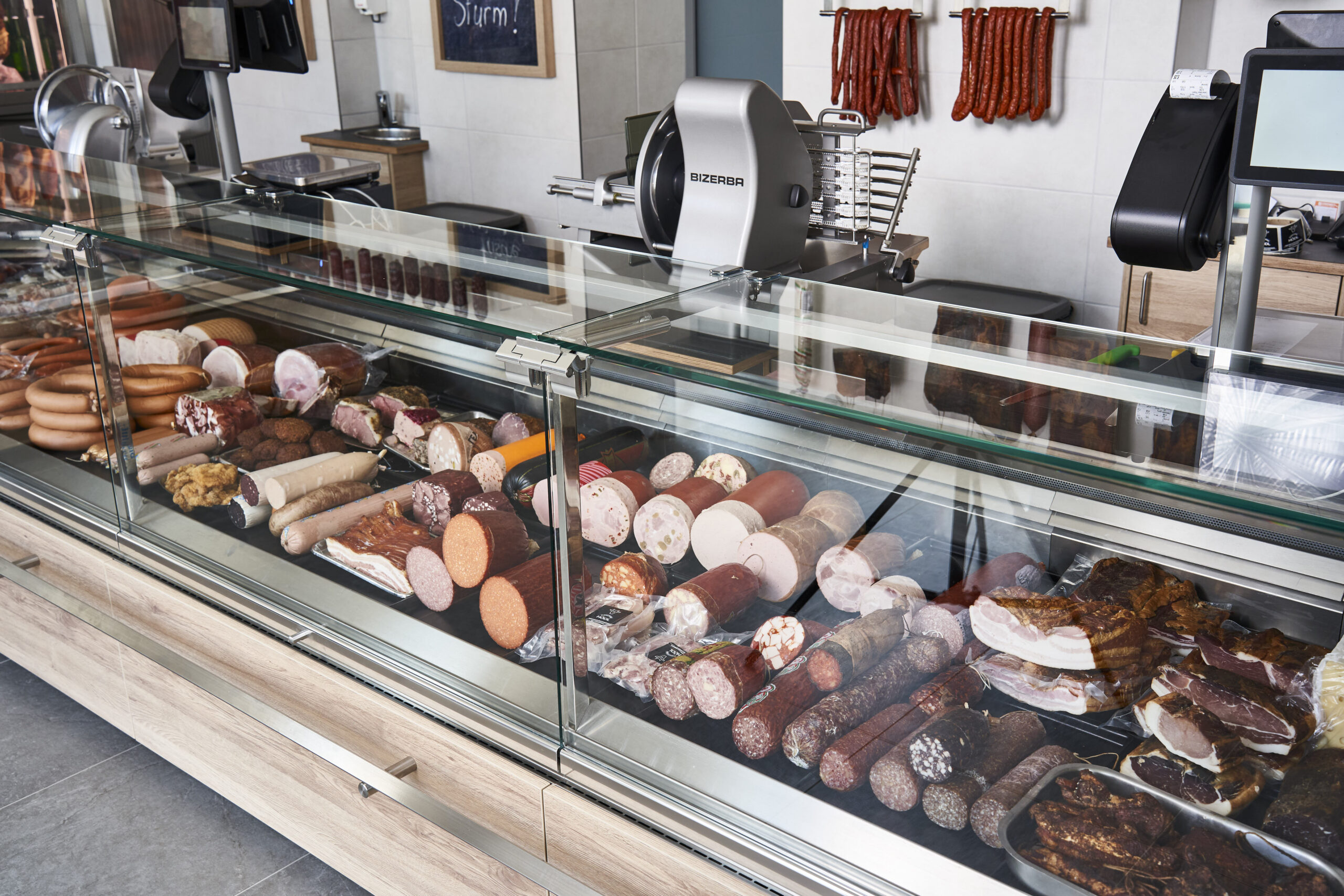 Eine Theke wie aus dem Lehrbuch: Die modern gestaltete Präsentationsfläche setzt die Fleisch- und Wurstwaren perfekt in Szene. Auch die neuen Wagen und Schneidemaschinen von Bizerba fügen sich harmonisch in das helle, zeitgemäße Ambiente der Fleischerei ein.